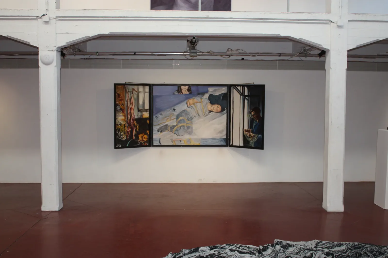 Brussels 1, 2018, vue d'exposition, La montagne, Bruxelles d'Aurian Guerard des Lauriers. Le triptyque ouvert sur un mur blanc, entre des piliers blancs, au-dessus d’un sol rouge.