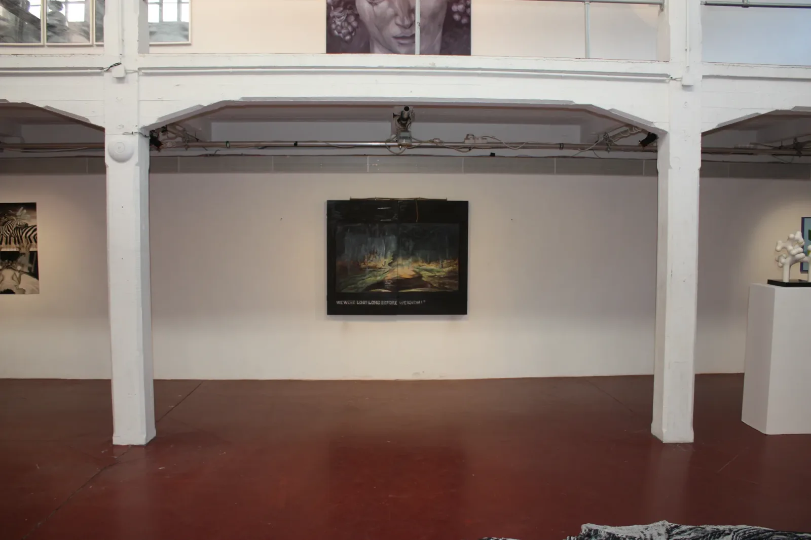 Brussels 6, 2018, vue d'exposition, La montagne, Bruxelles d'Aurian Guerard des Lauriers. Une peinture de forêt sombre sur le mur du fond de la galerie.