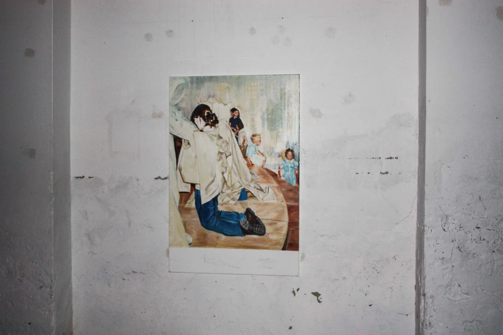 Holy Ghost Descent, installation view, 2018, vue d'exposition, La montagne, Bruxelles d'Aurian Guerard des Lauriers. Holy Ghost Descent sur un mur blanc usé. Une silhouette agenouillée en jean, drapée d’un tissu blanc, fait face à des enfants en bleu, sur un parquet arrondi.